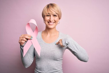 Kısa saçlı, kısa saçlı, göğüs kanseri olan genç bir kadın. Farkındalık pembe kurdeleli, süpriz yüzlü, kendini gösteren bir kadın.