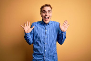 Sarı arka plan üzerinde sıradan çizgili tişört giyen genç ve yakışıklı bir adam çılgın ve başarıyı kollarını kaldırıp heyecanla haykırarak kutluyor. Kazanan konsept