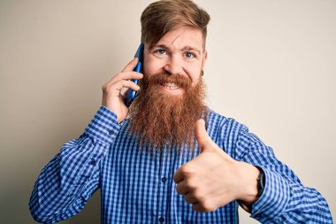 Kızıl saçlı, sakallı İrlandalı bir adam akıllı telefondan konuşuyor. Tecrit edilmiş arka planda, mutlu bir şekilde gülümsüyor. İşaret veriyor.
