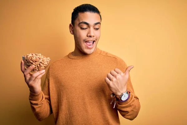 Young Brazilian Man Holding Bowl Healthy Salty Peanuts Isolated Yellow — Stock Photo, Image