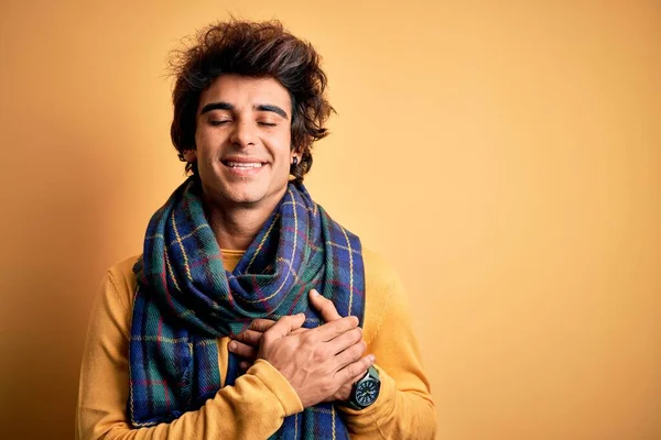 孤立した黄色の背景の上に立つカジュアルなスカーフを身に着けている若いハンサムな男は 目を閉じて胸の上に手で笑顔と顔に感謝のジェスチャー 健康コンセプト — ストック写真