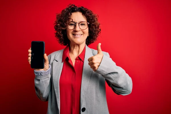 Среднего Возраста Кудрявая Женщина Держит Смартфон Показывая Экран Изолированном Красном — стоковое фото
