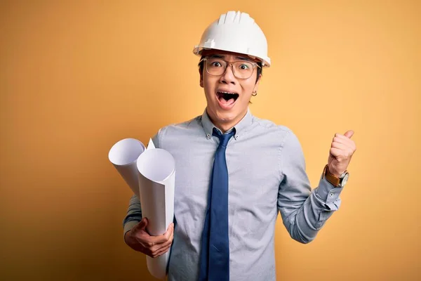 年轻英俊的中国建筑师 头戴安全帽 头戴安全帽 手握蓝图 高喊着自豪的口号 庆祝着胜利和成功 他激动地欢呼着 — 图库照片