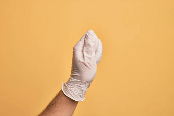 Mão Homem Jovem Caucasiano Com Luva Médica Sobre Fundo Amarelo — Fotografia de Stock