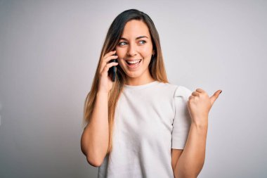 Genç, güzel, esmer bir kadın akıllı telefondan konuşuyor. Parmakla işaret ediyor ve gülümsüyor.