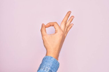İzole edilmiş pembe arka planda parmaklarını gösteren beyaz bir gencin eli işaret ediyor. Onaylama ifadesi parmaklarıyla sembol yapıyor.