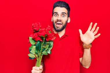 Sakallı, elinde gül buketi olan genç yakışıklı adam başarıyı mutlu bir gülümsemeyle ve kazanan yüz ifadesiyle kutluyor. 