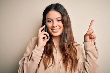 Genç, güzel, esmer bir kadın akıllı telefondan konuşuyor. Bir fikir ya da soru işareti ile şaşırmış, mutlu bir yüzle işaret ediyor.