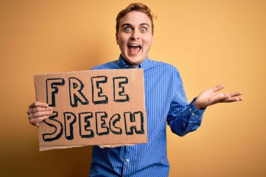 Genç ve yakışıklı kızıl saçlı adam özgürlük istiyor konuşma özgürlüğü mesajı ile bayrağı tutuyor zaferi mutlu bir gülümsemeyle kutluyor ve kazanan elleri kaldırarak ifade ediyor.