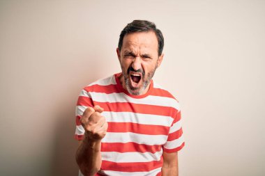 İzole edilmiş beyaz arka plan üzerinde duran sıradan çizgili tişört giyen orta yaşlı beyaz bir adam öfkeyle bağırırken kızgın ve öfkeli bir şekilde yumruğunu kaldırıyor. Öfke ve agresif kavram.