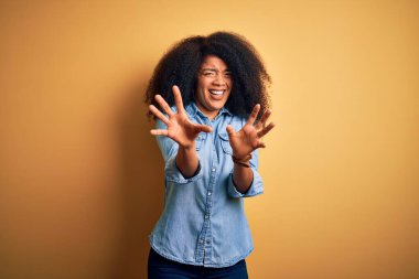 Sarıya boyanmış arka planda duran afro saçlı, genç ve güzel Afro-Amerikalı kadın korku ifadesinden korkuyor ve dehşete düşüyor. El hareketini durdur, şok içinde bağır. Panik konsepti.