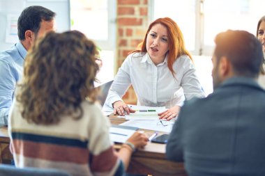 Birlikte çalışan bir grup işçi. Ofiste masa başında oturup konuşmak.