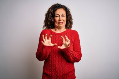 Orta yaşlı esmer kadın, günlük süveter giyer. İzole edilmiş beyaz arka plan üzerinde durur. İğrençtir ve tiksindirici bir yüz ifadesi takınır..