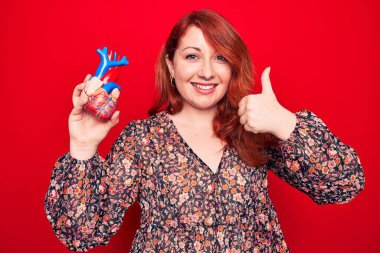 Genç, güzel, kızıl saçlı, sağlık hizmeti isteyen, geçmişi okuyup gülümseyen, mutlu ve olumlu gülümseyen, başparmağını kaldıran, mükemmel ve onay işareti yapan bir kadın.