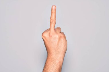 Hand of caucasian young man showing fingers over isolated white background showing provocative and rude gesture doing fuck you symbol with middle finger
