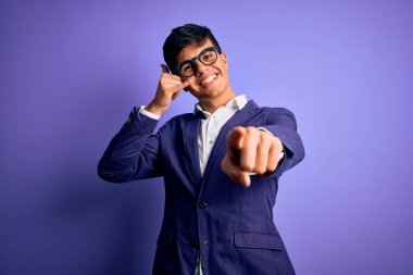 Ceket ve gözlük takan yakışıklı genç bir iş adamı mor arka planda gülümsüyor telefonda konuşuyor ve seni işaret ediyor. Ara beni..
