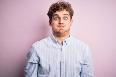 Sarışın, kıvırcık saçlı, beyaz arka plan üzerine çizgili gömlek giyen komik yüzlü, solgun yanaklı genç bir adam. Havayla şişmiş ağız, çılgın bir ifade..