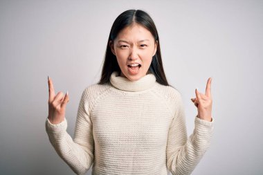 Genç ve güzel Asyalı bir kadın, sıradan bir süveter giyip izole bir arka planda durmuş çılgın bir ifadeyle elleri havada rock sembolü yaparken bağırıyor. Müzik yıldızı. Ağır konsept.