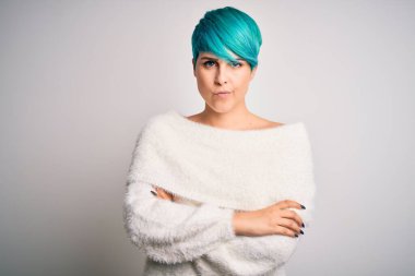 Young beautiful woman with blue fashion hair wearing casual sweater over white background skeptic and nervous, disapproving expression on face with crossed arms. Negative person.