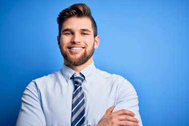 Sakallı, mavi gözlü, zarif gömlekli ve kravatlı genç, mutlu yüzlü, kollarını kavuşturup kameraya bakan genç bir iş adamı. Pozitif kişi.