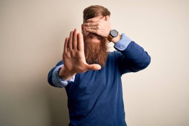 Yakışıklı, kızıl saçlı, sakallı bir iş adamı. İzole edilmiş arka planda duruyor. Gözlerini elleriyle kapatıyor. Utanç verici ve olumsuz bir kavram..