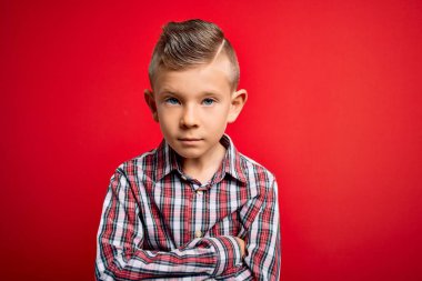 Mavi gözlü, kırmızı arka plan üzerinde şık gömlek giyen, kuşkucu ve gergin, yüzünde çapraz kollu tasvip etmeyen küçük beyaz bir çocuk. Negatif kişi.