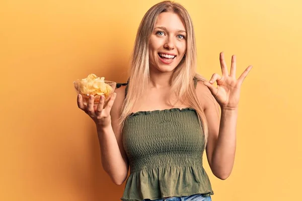 Mladá Blondýnka Drží Bramborový Lupínek Dělá Znamení Prsty Usmívá Přátelsky — Stock fotografie