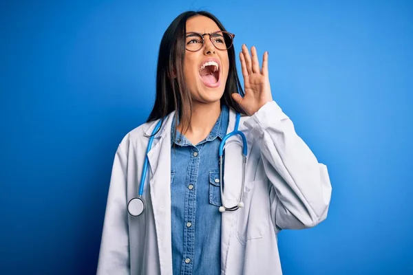 Młoda Piękna Lekarka Nosząca Stetoskop Okulary Niebieskim Tle Krzycząca Krzycząca — Zdjęcie stockowe