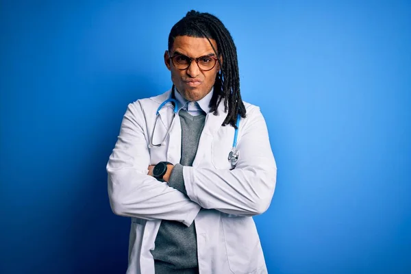 Young african american doctor man with dreadlocks wearing stethoscope and glasses skeptic and nervous, disapproving expression on face with crossed arms. Negative person.