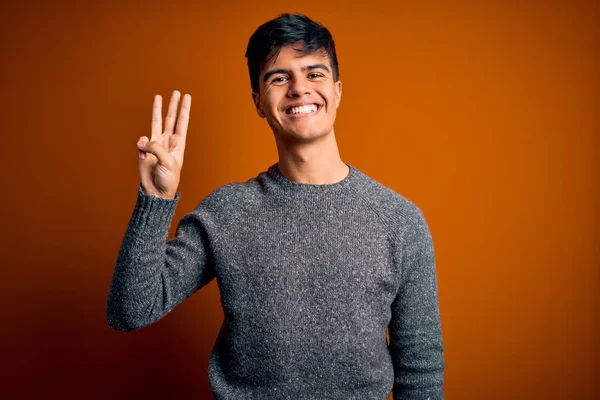 스웨터를 고립된 오렌지색 잘생긴 청년은 자신감 행복하게 웃으면서 손가락으로 가리켰습니다 — 스톡 사진