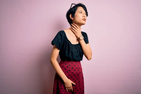 若いです美しいですアジアの女の子身に着けていますカジュアルドレス立って上の隔離されたピンクの背景感動的な痛みを伴う首 痛みを伴う喉のインフルエンザ 雲と感染 — ストック写真