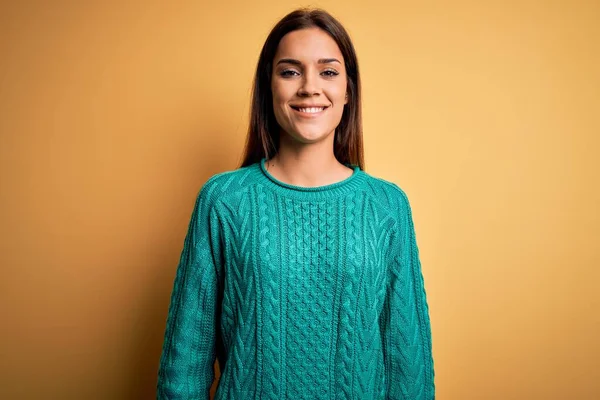 顔に幸せとクールな笑顔で黄色の背景に緑のカジュアルなセーターを着て若い美しいブルネットの女性 運のいい人 — ストック写真