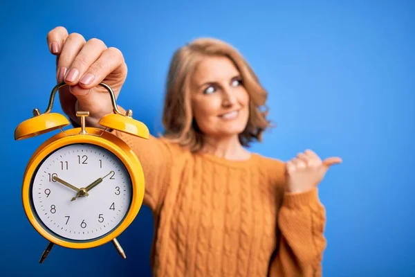 Middle Age Beautiful Blonde Woman Holding Vintage Alarm Clock Blue — Stock Photo, Image