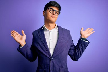 Ceket ve gözlük takan genç yakışıklı iş adamı. Mor arka plandan habersiz, kafası karışmış ve elleri ve kolları havada. Şüphe kavramı.