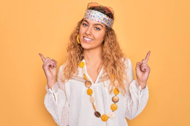 Mavi gözlü, güneş gözlüğü takan, kendine güvenen ve parmaklarını farklı yönlere çeviren güzel sarışın hippi kadın. Reklam için boşluk kopyala