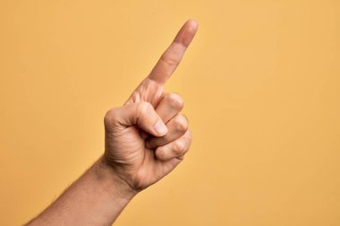 İzole edilmiş sarı arka planda parmaklarını gösteren beyaz bir gencin eli işaret parmağı kullanarak bir numarayı sayıyor, fikir ve anlayış gösteriyor.