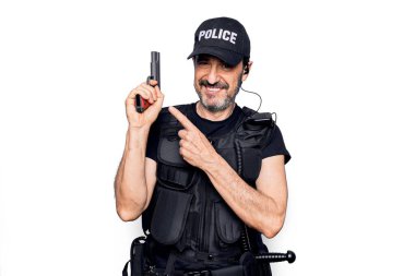 Polis üniforması giyen, kurşun geçirmez yelek giyen, elinde silah tutan orta yaşlı, yakışıklı bir polis.