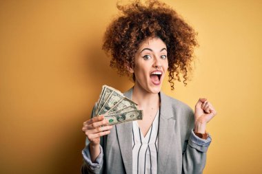 Kıvırcık saçlı ve piercing 'li genç bir kadın elinde dolarlarla gururla bağırıyor ve zaferi ve başarıyı kutluyor. Çok heyecanlı, coşkulu bir duygu.