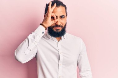 Gündelik kıyafetler giyen genç Arap adam el hareketleriyle gülümsüyor ve mutlu yüzüyle parmaklarının arasından bakıyor.. 