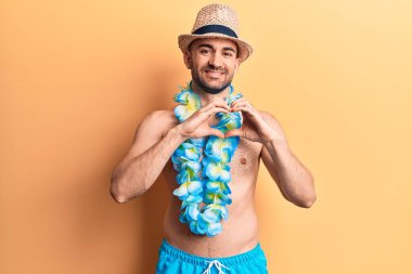 Yakışıklı, kel, mayo giymeyen ve Hawaii 'de gülümseyen elleri ile kalp sembolü yapan genç bir adam. romantik kavram. 
