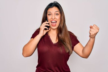 Genç İspanyol kadın akıllı telefondan konuşuyor. Arka planda, gururla bağırıyor, zaferi ve başarıyı kutluyor. Çok heyecanlı, coşkulu bir duygu.