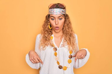 Genç, sarışın, mavi gözlü, güneş gözlüklü, aksesuar takan, reklam veren, şaşırmış yüzlü ve ağzı açık genç bir hippi.