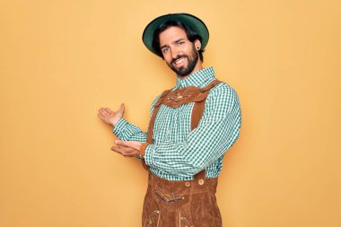 Almanya festivali için geleneksel Alman Ekim Festivali kıyafeti giyen yakışıklı genç adam gülümseyerek doğal bir şekilde içeri girmeye davet ediyor.