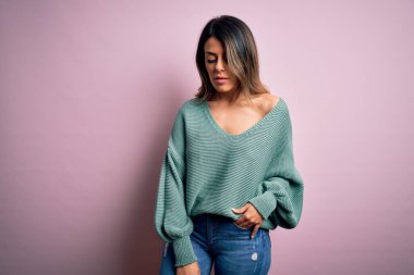 Moda kıyafetleri giyen genç ve güzel bir kadın. Manken, sokak tarzı giyiniyor. Pembe arka planda dikiliyor.