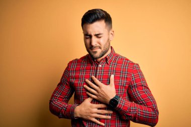 Genç ve yakışıklı bir adam, hazımsızlık, acı verici bir hastalık yüzünden izole edilmiş sarı arka planda ayakta dikiliyor. Ache kavramı.