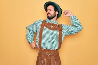 Almanya festivali için geleneksel Alman Ekim Festivali kıyafeti giyen genç yakışıklı adam geriye doğru uzanıyor, yorgun ve rahat, uykulu ve sabahın erken saatlerinde esniyor.