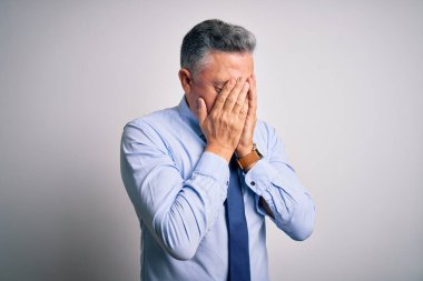 Orta yaşlı, yakışıklı, gri saçlı, zarif gömlekli ve kravatlı bir iş adamı. Ağlarken yüzünü ellerle kapatıyor. Depresyon kavramı.