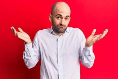 Zarif tişört giyen yakışıklı kel adam habersiz ve kolları açık, hiçbir fikrim yok ve şüpheli bir yüzüm var.. 