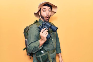 Kaşif kıyafetleri giyen genç İspanyol adam elinde dürbünle korkmuş ve ağzı açık şaşkınlık içinde, inançsız bir yüz. 