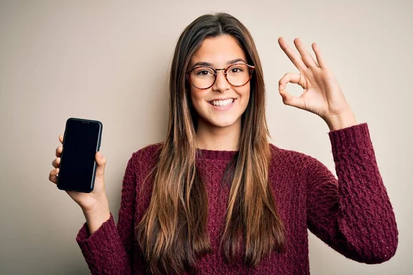 Menina Bonita Nova Usando Óculos Mostrando Smartphone Sobre Fundo Branco — Fotografia de Stock